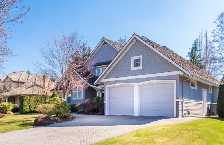 A beautiful grey two-story house with a white double garage and paved driveway representing home equity and refinance savings.
