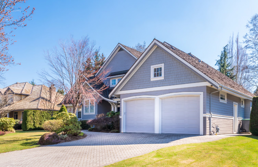 A beautiful grey two-story house with a white double garage and paved driveway representing home equity and refinance savings.