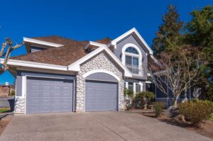 Modern grey two-story house with stone accents and a garage
