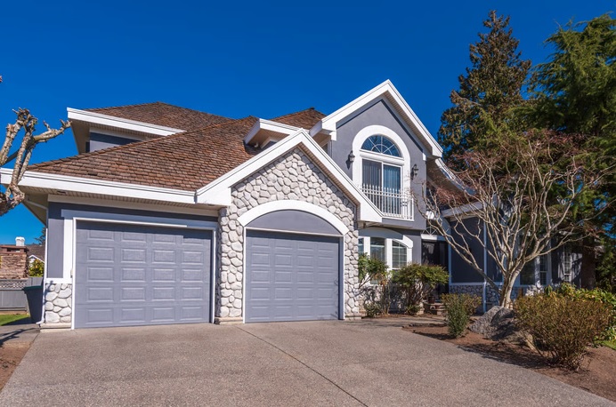 Modern grey two-story house with stone accents and a garage